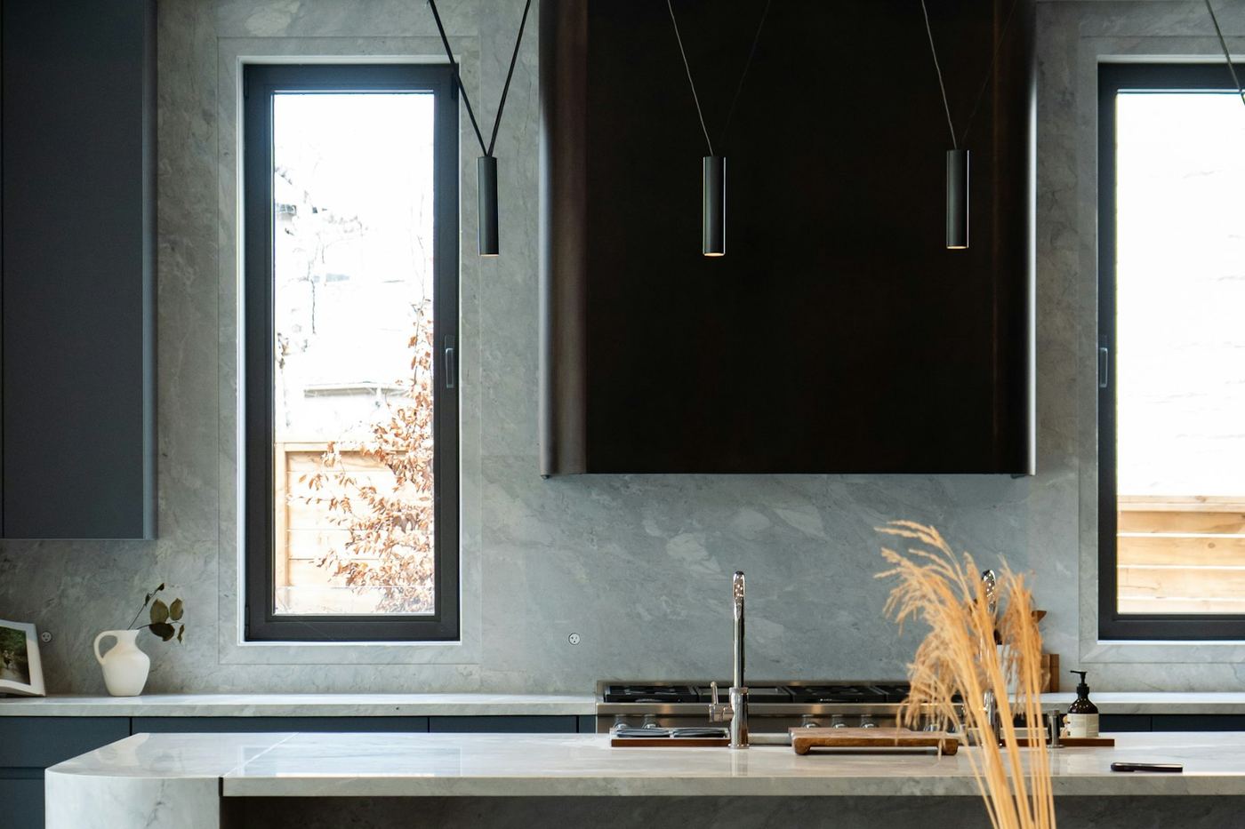 Contemporary kitchen with slimline pendant lights above a stone island
